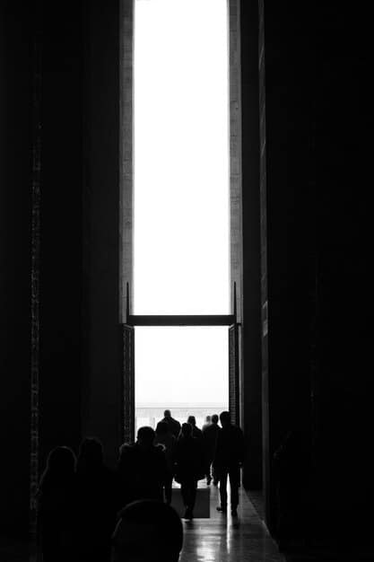 A silhouette of a student praying in a school hallway, with light streaming in from a nearby window. The image should be respectful and non-intrusive, representing individual prayer rather than school-sponsored religious activities.
