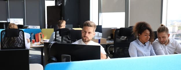 A close-up of a modern office environment with employees working on computers. Focus on a screen displaying a data protection policy document. Visible elements include company logos and employee badges.