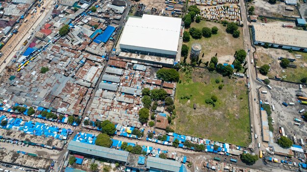 An aerial view of a neighborhood with a large industrial factory located adjacent to residential homes. The image emphasizes the close proximity of the factory to the community and potential environmental risks, contrasting green residential areas.