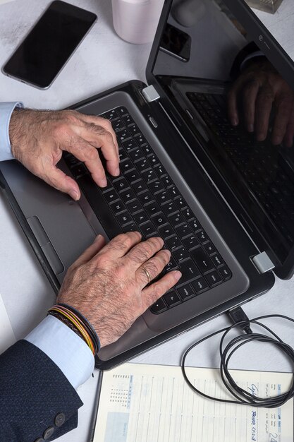 A close-up of a journalist's hands typing rapidly on a laptop, emphasizing the digital tools and intensive research involved in modern investigative journalism. The lighting is focused on the keyboard and the screen's glow illuminates the journalist's face.