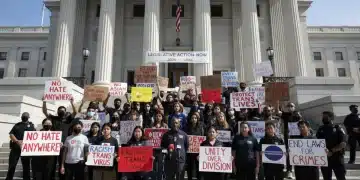 Activists advocating for stronger hate crime legislation in 2026, holding signs and banners.